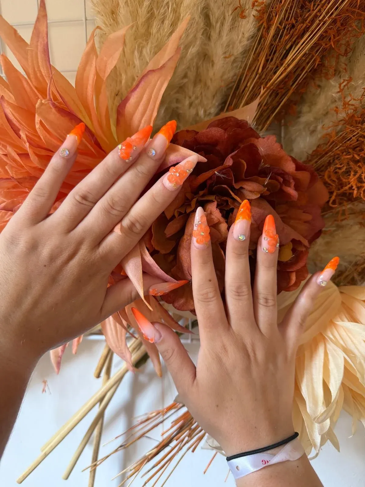 Ongles amande longs dégradé orange avec fleurs en relief et strass